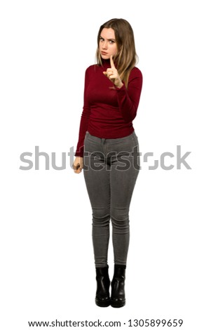 A full-length shot of a Teenager girl with turtleneck frustrated and pointing to the front over isolated white background