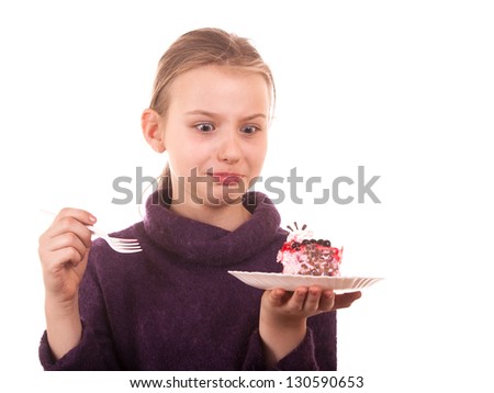 Pretty young girl looking at cake on white