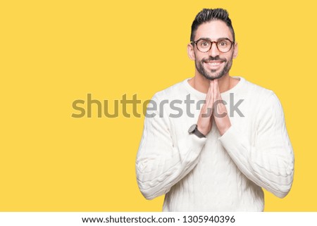 Young handsome man wearing glasses over isolated background praying with hands together asking for forgiveness smiling confident.