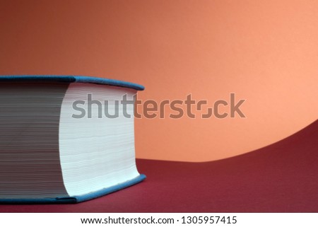 Education and rising concept. Thick book for personal development on red and coral background