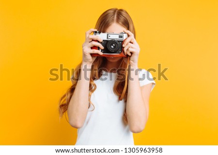 beautiful girl with a camera in her hands, on a yellow background, a woman takes pictures