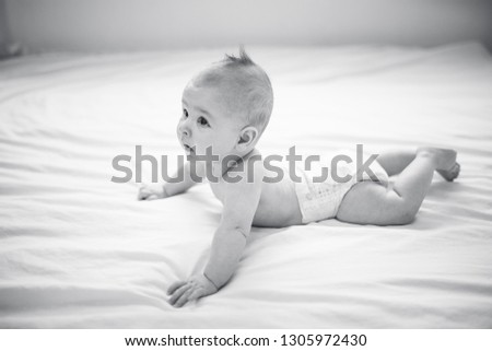 Black and white image of adorable baby lying on bed