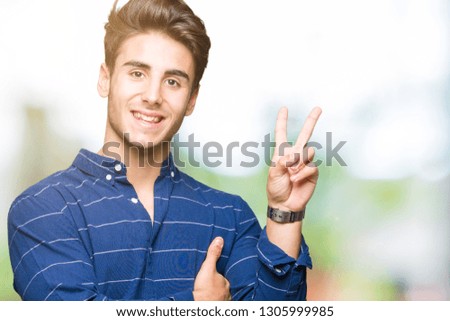 Young handsome man wearing navy shirt over isolated background smiling with happy face winking at the camera doing victory sign. Number two.