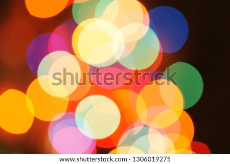 Multi-color holiday garland. Garland is blurred. Many colorful round lights. Fully defocused photo. Blurred background and foreground. Holiday mood. New Year and Christmas is coming.