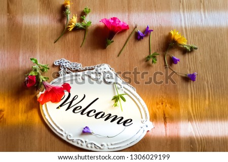 The phrase "welcome home", composed of wild flowers (bells, dandelions) on a wooden table. Retro-style. Concept of home, hospitality, hotel, friendship