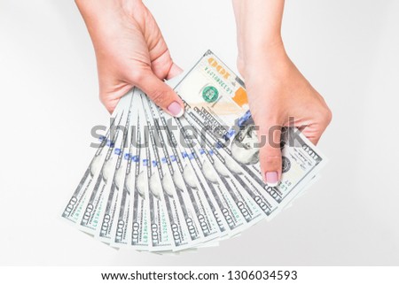 Closeup up view of white female hands holding many 100 dollars paper bills isolated on white background. Horizontal color photography.