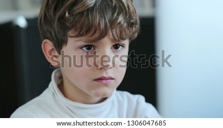 Close-up of child face looking at computer. Young boy starring laptop screen hypnotized by online content on the internet