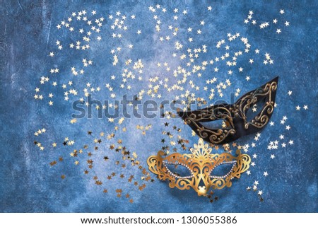 Two carnival mask and golden stars on blue background. Top view, copy space. Carnival party celebration concept.