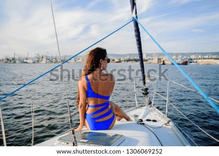 Beautiful young woman in a blue swimsuit relaxing on a yacht in the sea on a sunny summer day