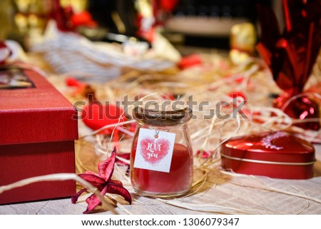 I love you Glass jar filled with red sand placed on wooden table with straw