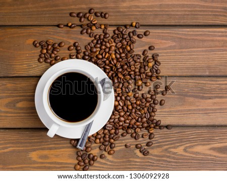 Coffee cup, beans and spoon on wooden background on the table. Perfect breakfast in the morning. Rustic style, top view