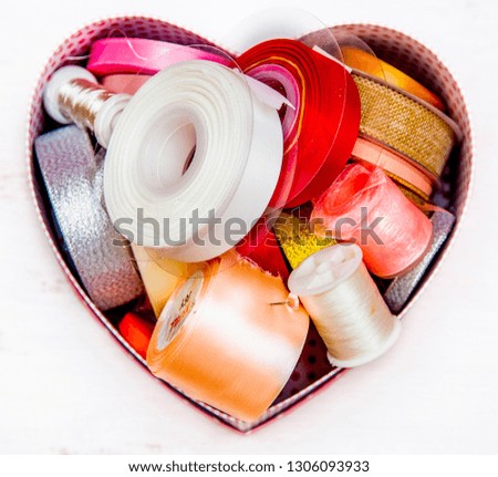 box in the shape of a heart with skeins of colorful ribbons for needlework, isolated
