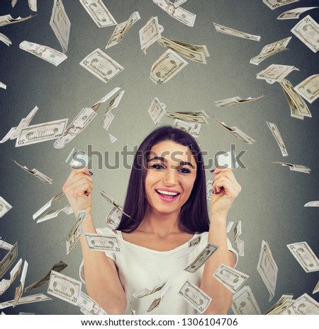 Happy debt free woman holding a credit card cut in two pieces under money rain
