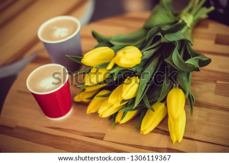 Yellow flowers tulips and two glasses of cappuccino coffee on a wooden table Royalty-Free Stock Photo #1306119367