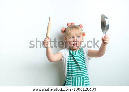 toddler in role of angry housewife with pink curlers and  frying pan