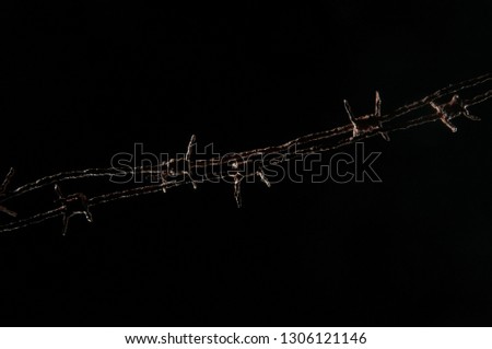 Two strips of barbed wire on a diagonal on a black background
