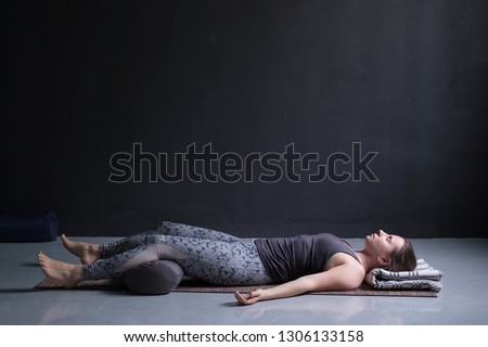 woman working out, doing yoga exercise on wooden floor, lying in Shavasana Royalty-Free Stock Photo #1306133158