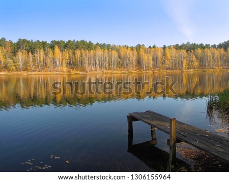 A little wharf for boats or fishing, and autumn forest and its reflection in the water on the background. Picture taken on the Deep Lake, Kazan, Russia