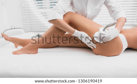 Beautiful woman having cavitation, procedure removing cellulite on legs and buttocks at beauty clinic Royalty-Free Stock Photo #1306190419
