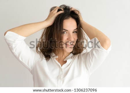 Excited young woman rumpling hair and looking at camera. Playful pretty lady. Excitement concept. Isolated front view on white background.