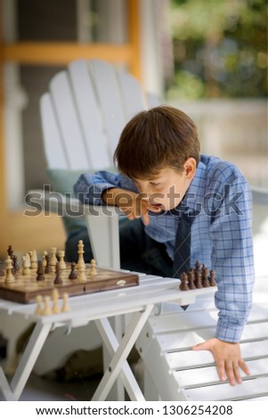 Boy sitting outside playing chess.