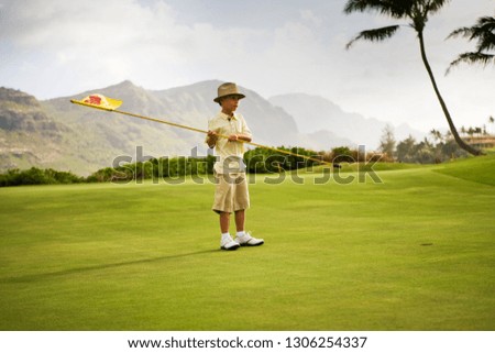 Young boy holds a golf flag.
