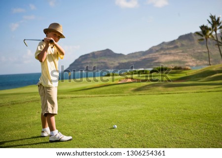 Young boy looks up as he prepares to swing a golf club.