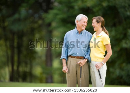 Older man and daughter laughing on golf course