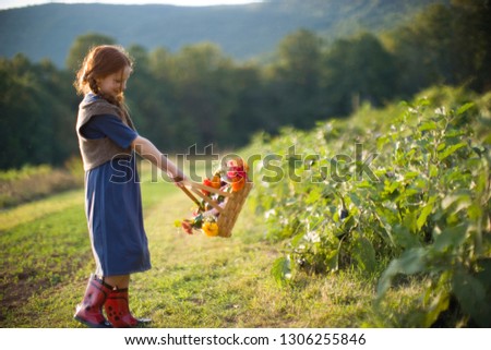 Young girl swinging a basket of flowers on a farm.