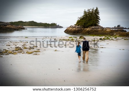 Young girl exploring the beach with her grandfather.