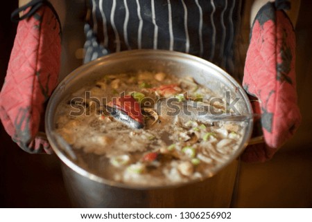 Pot of fish soup being held.
