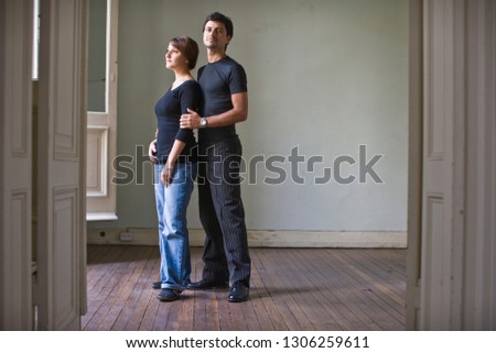 Portrait of a mid-adult man standing holding his wife's arm in a room.