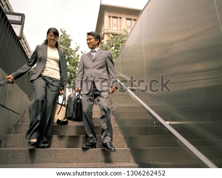 Businessman and woman walking down some steps.