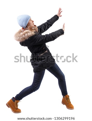 back view of woman in winter jacket pushes wall.  Isolated over white background. Rear view people collection.  A girl in a warm park with fur is protected by her hands from something above.