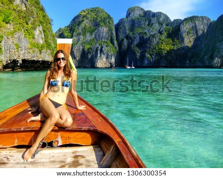 Young woman sitting at the front of longtail boat in Maya Bay on Phi Phi Leh Island, Krabi Province, Thailand. This island is part of Mu Ko Phi Phi National Park.