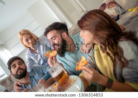 Smiling friends eating pizza and drinking beer at home.Leisure, people,food and happiness concept.