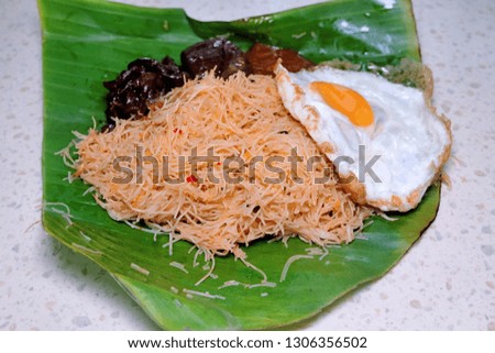 A picture of fried rice noodle with sunrise egg, "sambal sotong" and shrimp sauce for breakfast in banana leaf. Malaysian love to have heavy breakfast.
