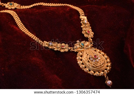 Designer beautiful golden necklace closeup macro image on red background.