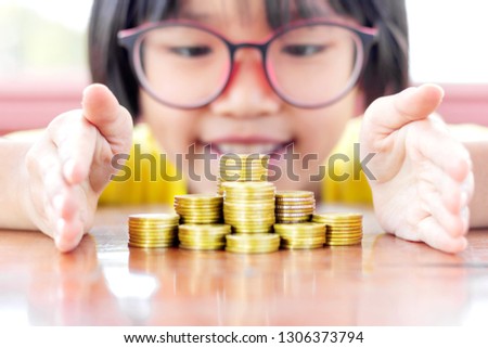 Child hand protecting stacked coins.coin stack growing graph selective focus