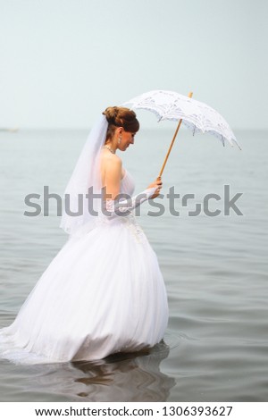 bride with a wedding umbrella in the water