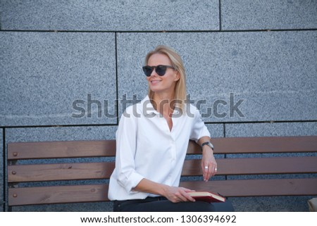 happy woman in sunglasses sitting with book