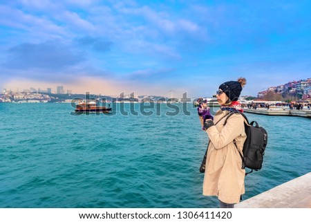 Beautiful woman traveler tourist take pictures of Bosphorus,a popular destination in Uskudar town,Istanbul,Turkey
