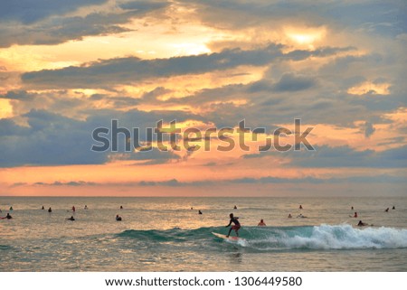 Stunning sunset on the beach overlooking the ocean and the waves. Surfers catch the wave. 