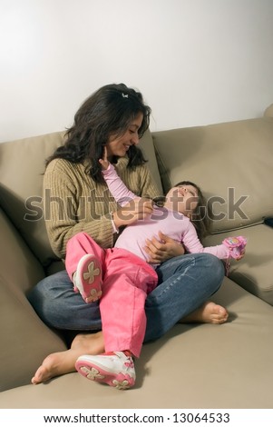Mother and daughter playing together on their living room couch