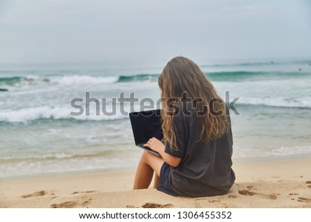 Young girl working at the computer on the beach. The freelancer working on the beach. Beach of the Indian ocean. Sri-lanka.
