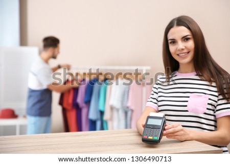 Female shop assistant with payment terminal at counter. Space for text