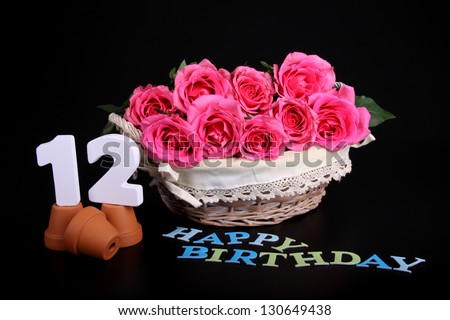 Number of age in a colorful studio setting with pink roses against a black background