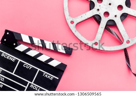 Filmings concept. Clapperboard and film stock on pink background top view copy space