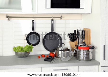 Set of clean cookware, utensils and products on table in modern kitchen Royalty-Free Stock Photo #1306510144