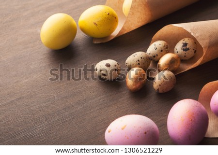 Colourful quail eggs in craft paper cornets on dark background